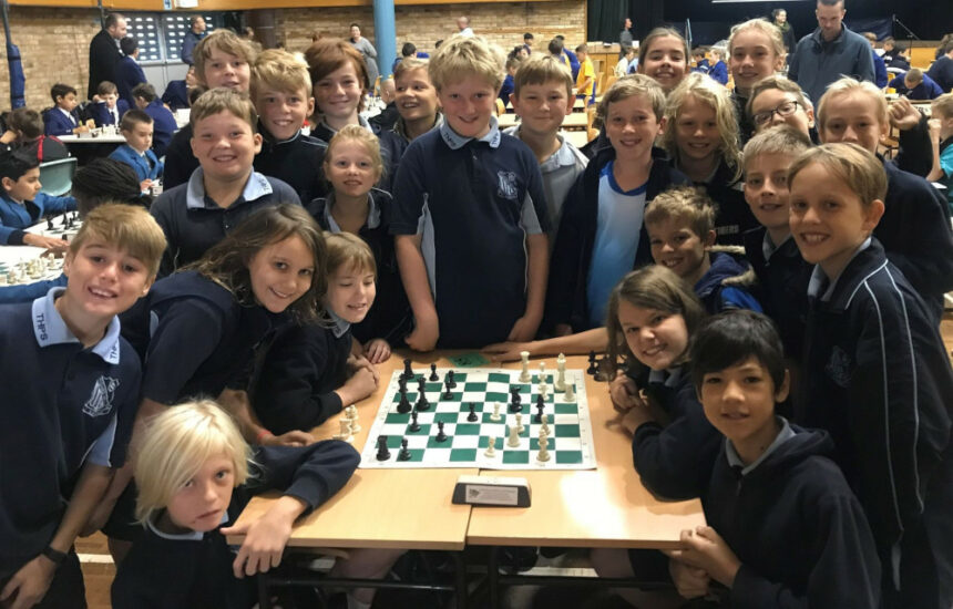 Grupo de niños sonríe a la cámara en una competición de ajedrez.
